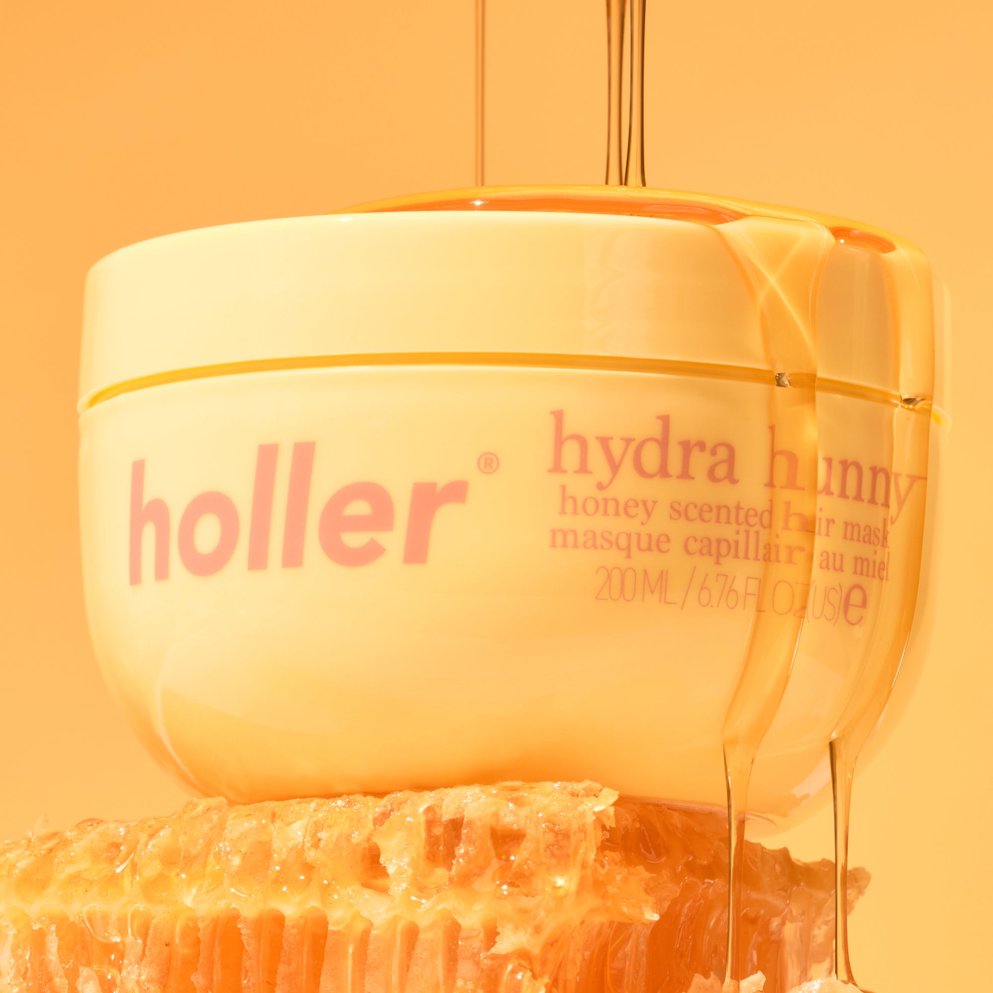 Holler honey scented hair mask with honey being poured over it on an orange background