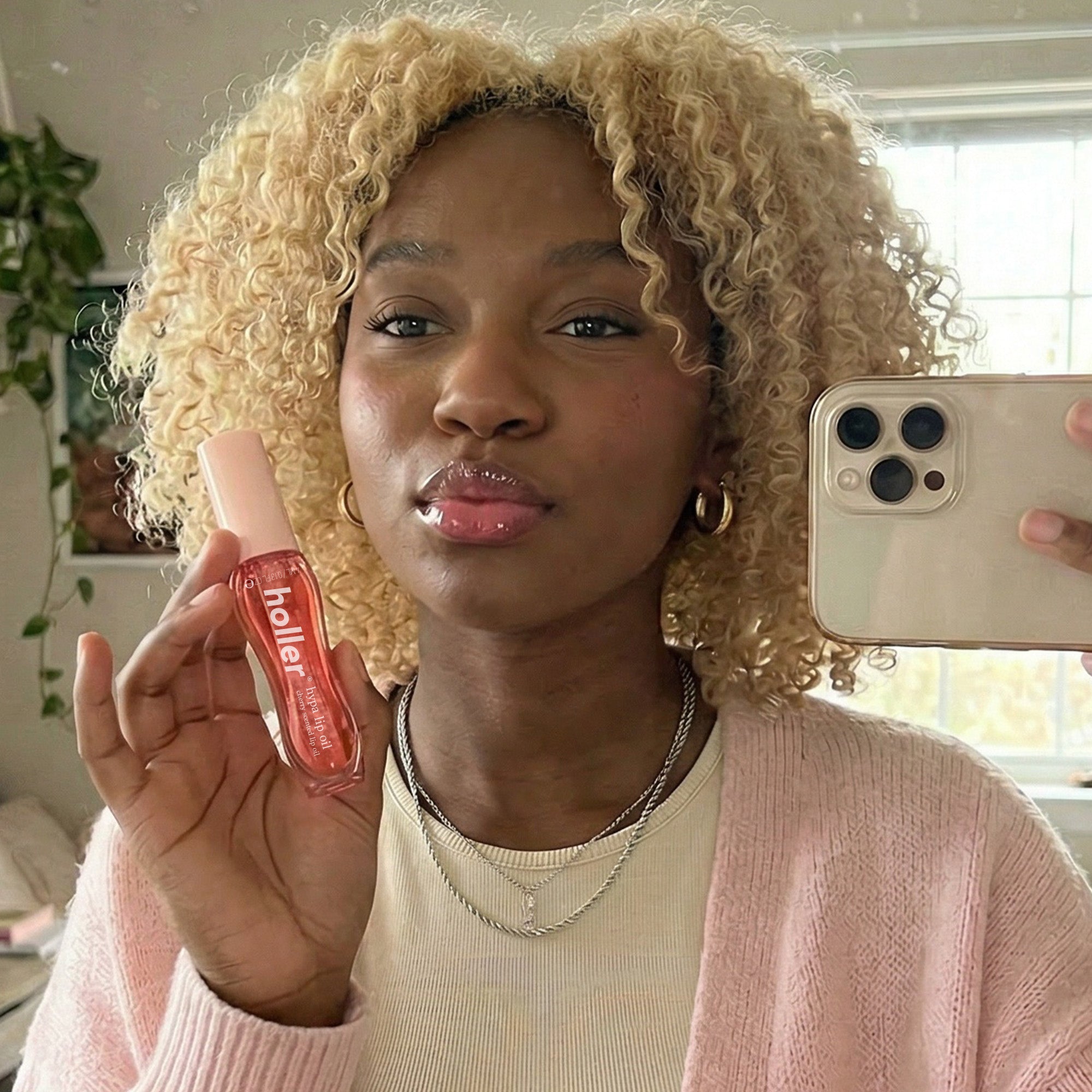Person holding a phone and a bottle of 'heller' product indoors.