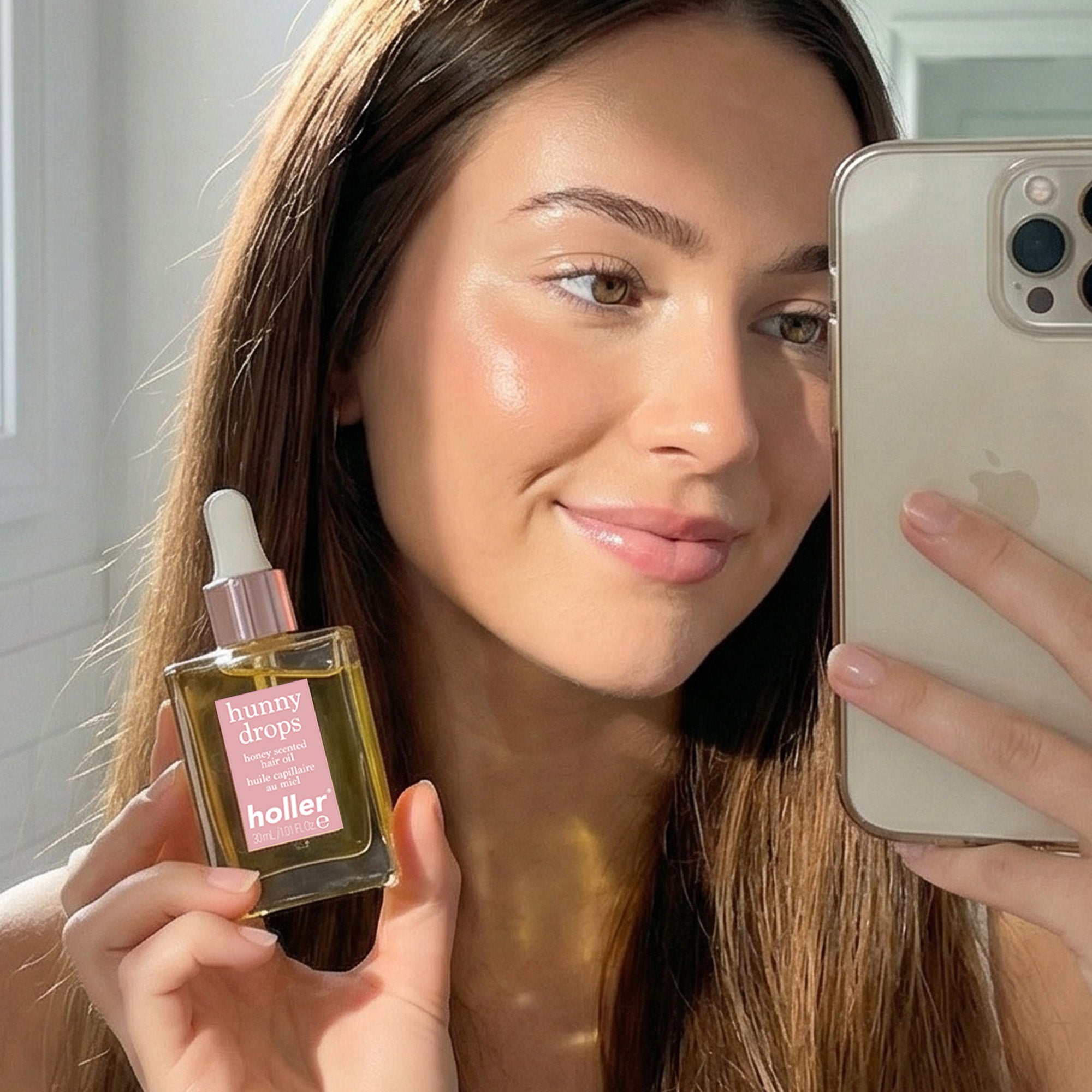 Woman taking a mirror selfie with a dropper bottle labeled 'holler' in her hand.